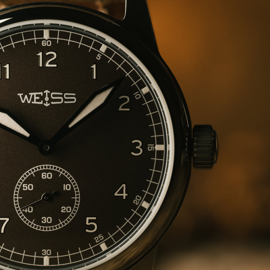 Close-up of a brown watch with 'WEISS' branding on a brown background
