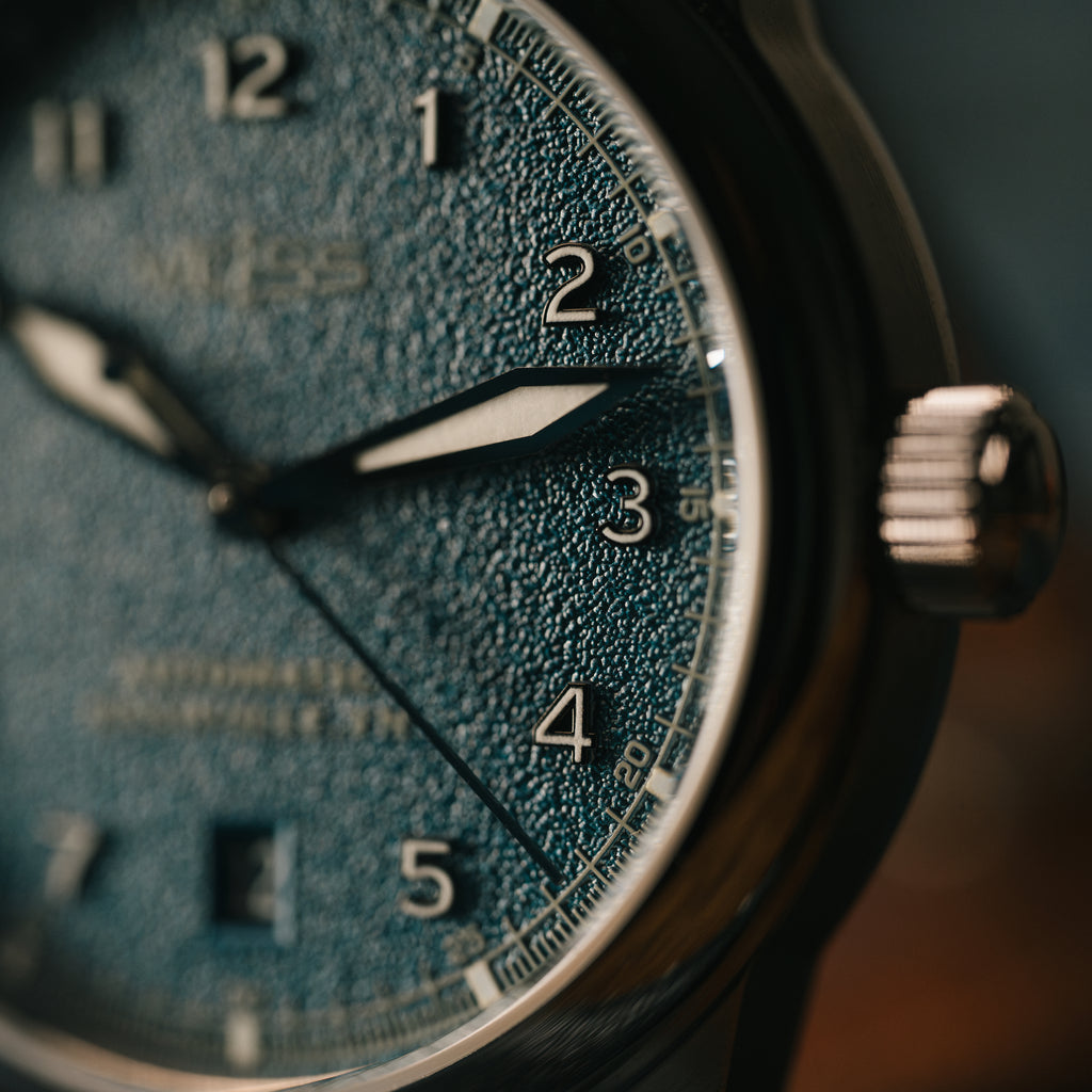 Close-up of a weiss watch face with a textured blue dial 